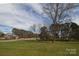 Well-manicured front yard with a white fence, mature trees, and a glimpse of the brick home at 11215 Idlewild Rd, Matthews, NC 28105