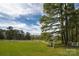 Expansive front yard with lush green grass, white fencing, and a glimpse of the house in the background at 11215 Idlewild Rd, Matthews, NC 28105