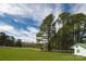 Beautiful front yard with mature trees, green lawn, and a white-sided outbuilding at 11215 Idlewild Rd, Matthews, NC 28105