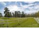 Large front yard with a bright green lawn and a classic white fence along the property line at 11215 Idlewild Rd, Matthews, NC 28105