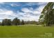 Expansive grassy area bordered by trees and white fencing at 11215 Idlewild Rd, Matthews, NC 28105