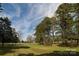 Expansive lot with lush green grass and mature trees under a partly cloudy sky at 11215 Idlewild Rd, Matthews, NC 28105