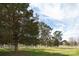 Expansive front yard showcases a large shade tree and a white fence under a partly cloudy sky at 11215 Idlewild Rd, Matthews, NC 28105