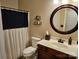 Cozy bathroom with a dark vanity, decorative mirror, modern toilet, and a shower curtain with stylish buttons at 14117 Hiawatha Ct, Huntersville, NC 28078