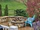 Cozy stone fire pit area with stacked Adirondack chairs, mature landscaping, and black metal fencing at 14117 Hiawatha Ct, Huntersville, NC 28078