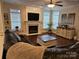 Cozy living room with fireplace, ceiling fan, large sofa, and natural light from multiple windows at 14117 Hiawatha Ct, Huntersville, NC 28078