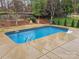 Backyard pool featuring a stamped concrete surround, metal handrails, and mature landscaping at 14117 Hiawatha Ct, Huntersville, NC 28078