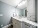 Bright bathroom featuring a marble countertop, vanity with storage, and a large, well-lit mirror at 1623 Geneva Ct, Charlotte, NC 28209