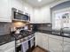 Updated kitchen featuring stainless appliances, granite countertops, tile backsplash and custom white cabinetry at 1623 Geneva Ct, Charlotte, NC 28209