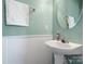 Bathroom featuring a white pedestal sink, wainscoting and a large round mirror at 2012 Oakstone Dr, Monroe, NC 28110