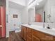 Bathroom featuring double sinks and well-lit vanity area, next to a toilet and pink shower curtain at 2012 Oakstone Dr, Monroe, NC 28110