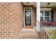 Inviting front porch with brick steps, black front door with a wreath and cozy seating area at 205 Cowboys Cir, Rock Hill, SC 29732