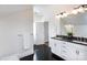 Bathroom with double sinks, black countertops, white cabinetry, and black hardwood flooring at 4717 Doris Ave, Charlotte, NC 28205