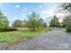 Wide front yard, gravel driveway, with new fence, green grass and mature trees under a blue sky at 6282 Richburg Rd, Great Falls, SC 29055