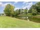 Beautiful backyard featuring lush green grass and mature trees along the water's edge at 7790 Blackwood Rd, Denver, NC 28037