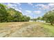 The grassy backyard leads to the waterfront, surrounded by mature trees and partially cloudy blue skies at 7790 Blackwood Rd, Denver, NC 28037