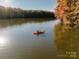 Scenic lake view featuring a person kayaking amidst vibrant autumn trees and serene waters at 9408 Munsing Dr # 149, Charlotte, NC 28269