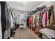 Walk-in closet with rows of hanging clothes, shelving, and a vanity table with a stool at 12502 Bending Branch Rd, Charlotte, NC 28227