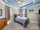 Cozy bedroom with a tray ceiling, ceiling fan, and natural light from the windows at 810 Lake Wright Rd, China Grove, NC 28023