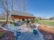 Picturesque outdoor kitchen with a grill, seating area, and lush landscaping in a tranquil setting at 810 Lake Wright Rd, China Grove, NC 28023