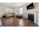 Bright living room featuring a fireplace, wood floors, and a comfortable beige sofa with natural light at 9706 Tea Garden Dr, Gastonia, NC 28056