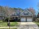 Charming two-story home featuring stone accents, a two-car garage, and a well-maintained front yard under a clear blue sky at 12217 Greymore Ct, Charlotte, NC 28277