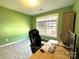 Bright, green home office with gray carpet, large window, and desk with desktop computer and office chair at 12217 Greymore Ct, Charlotte, NC 28277