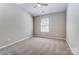 A neutral, carpeted bedroom with a ceiling fan and bright window at 16729 Timber Crossing Rd, Charlotte, NC 28213