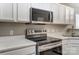 Close-up of kitchen appliances, including a range and microwave, with white cabinets at 16729 Timber Crossing Rd, Charlotte, NC 28213