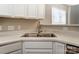 A corner kitchen sink, with white cabinets and light countertops, near a window at 16729 Timber Crossing Rd, Charlotte, NC 28213