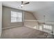 Bright carpeted loft with ceiling fan, large window, and white railing at 16729 Timber Crossing Rd, Charlotte, NC 28213