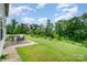 Expansive backyard featuring a patio with dining set, grill, and plenty of green space surrounded by trees at 16839 Cozy Cove Rd, Charlotte, NC 28278