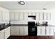 Well-lit kitchen featuring white cabinets, black appliances, and tile backsplash for modern charm at 269 Loch Stone St, Fort Mill, SC 29715