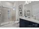 Tiled bathroom with glass shower door, navy cabinets, and elegant fixtures at 324 Basil Dr, Indian Trail, NC 28079