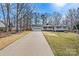 Single-story home with a long driveway leading to an attached garage, surrounded by mature trees at 1140 Knollwood Dr, Claremont, NC 28610