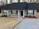 Inviting single-story house features a black front door framed by white columns and newly installed dark roof at 1311 Meadow Ave, Kannapolis, NC 28083