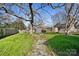 Lush backyard featuring green grass, mature trees, a firepit, and two sheds at 1509 Harrill St, Charlotte, NC 28205