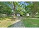 Lush backyard with mature trees, a fire pit seating area and storage sheds for outdoor living at 1509 Harrill St, Charlotte, NC 28205