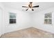 Bright bedroom featuring neutral carpet, two windows, and a ceiling fan at 1509 Harrill St, Charlotte, NC 28205