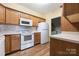 Updated kitchen with white appliances, wooden cabinets and light countertops and backsplash at 16312 Redstone Mountain Ln, Charlotte, NC 28277