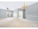 Bright, carpeted living room featuring French doors, chandelier, and neutral paint, offering a calming space at 16312 Redstone Mountain Ln, Charlotte, NC 28277