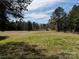 A sprawling green field is bordered by a classic wooden fence and mature trees, offering a serene and private setting at 18637 Davidson Concord Rd, Davidson, NC 28036