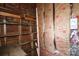 Unfinished storage area with exposed insulation, shelving and brick foundation at 2825 Bancroft St # C, Charlotte, NC 28206