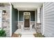 Covered porch with a dark wood door, gray siding, and stone accents at 4223 Black Ct # 195, Harrisburg, NC 28075