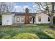 Backyard view of home with brick chimney, exterior door, and green lawn at 4309 Woodglen Ln, Charlotte, NC 28226