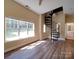 View of the living room with hardwood floors, a large window, ceiling fan, and a spiral staircase at 6724 Mallard Park Dr, Charlotte, NC 28262