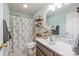 Bright bathroom featuring a vanity, patterned shower curtain, and wall shelves for storage at 7025 Ridgeway Rd, Stanley, NC 28164