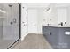 Modern bathroom featuring tiled shower with glass door, grey vanity and white door at 11327 James Coy Rd, Davidson, NC 28036