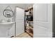 Bright mudroom with a white vanity, sink, round mirror, and pantry with open shelving at 1501 Laurel Ln, Gastonia, NC 28054
