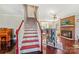 View of the staircase with red accents, leading to a living area with a fireplace and comfortable seating at 207 Crossing Ave, Belmont, NC 28012